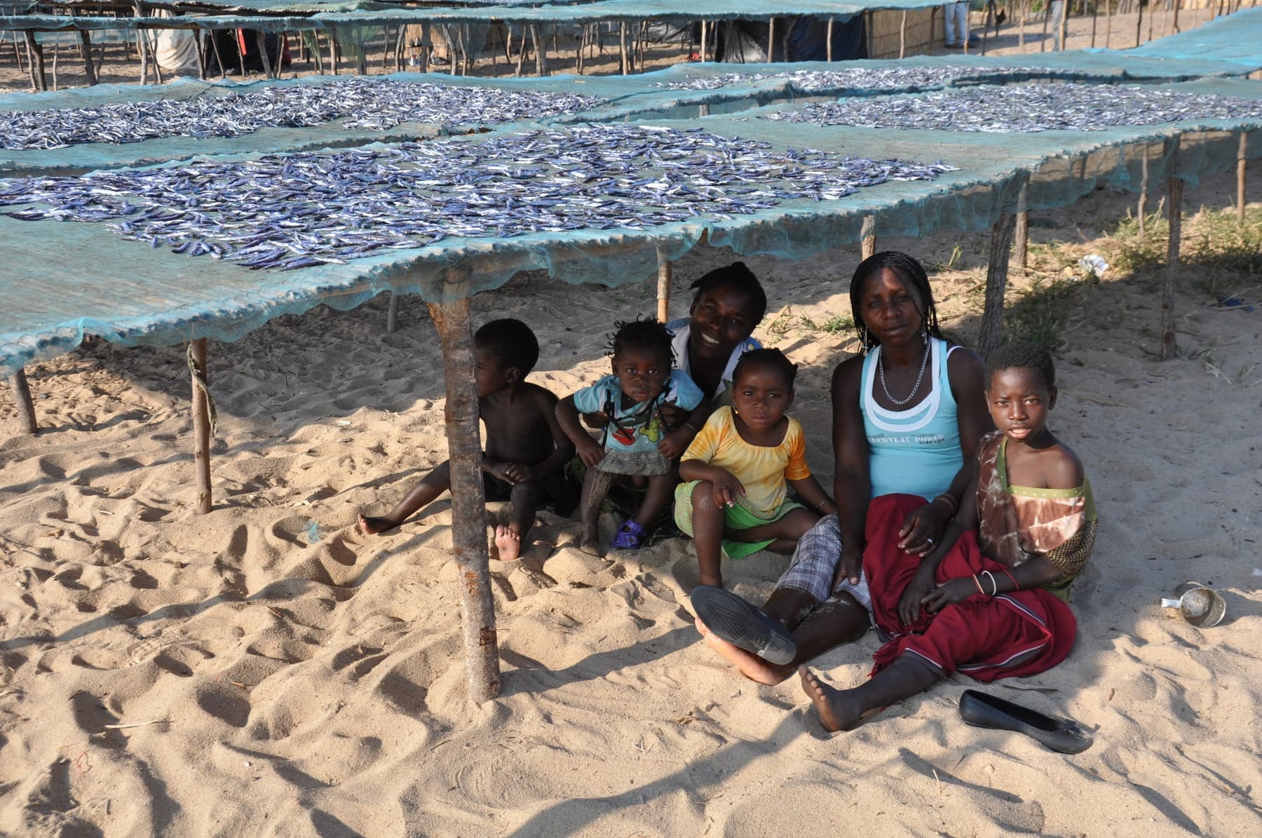 A family rests in the shade of fish-drying nets, Lake Niassa
